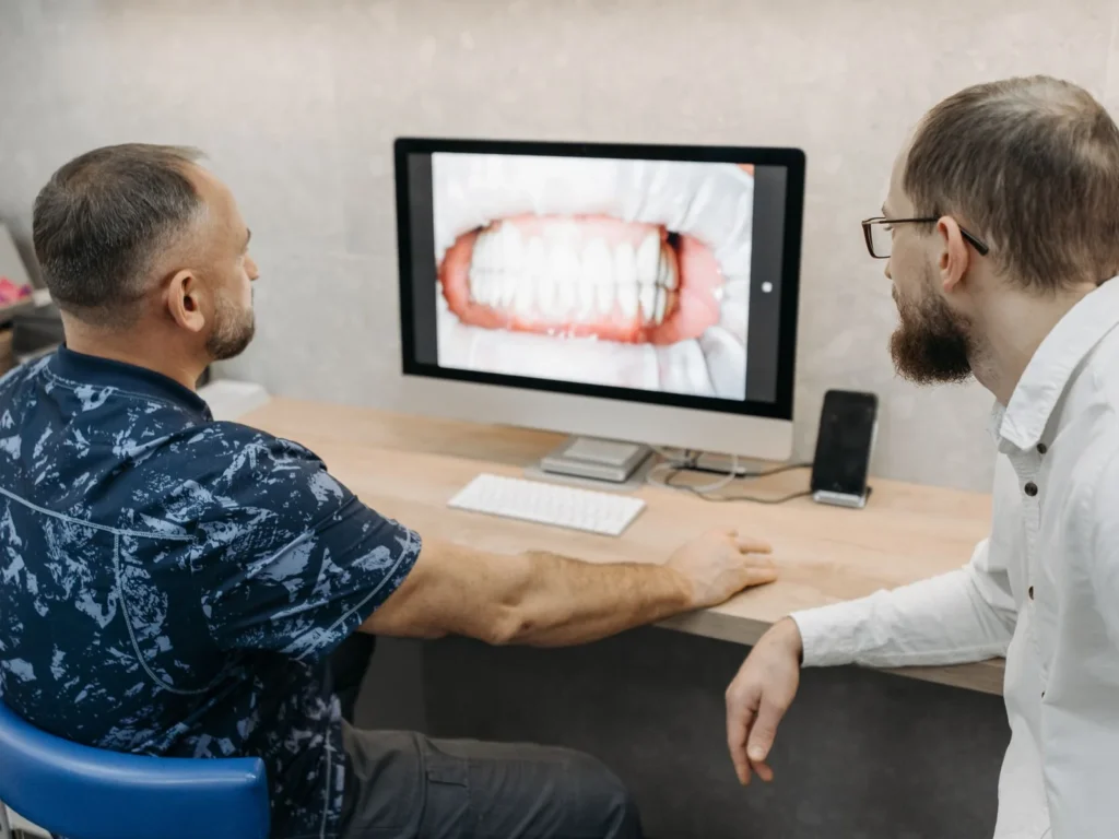 A dentist discusses a digital image of teeth with a patient.