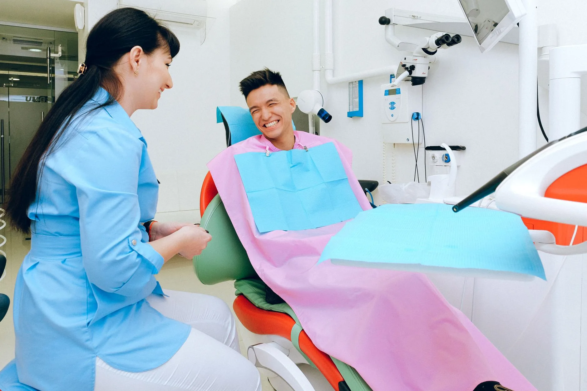 A dental professional talks with a smiling patient seated in a treatment chair