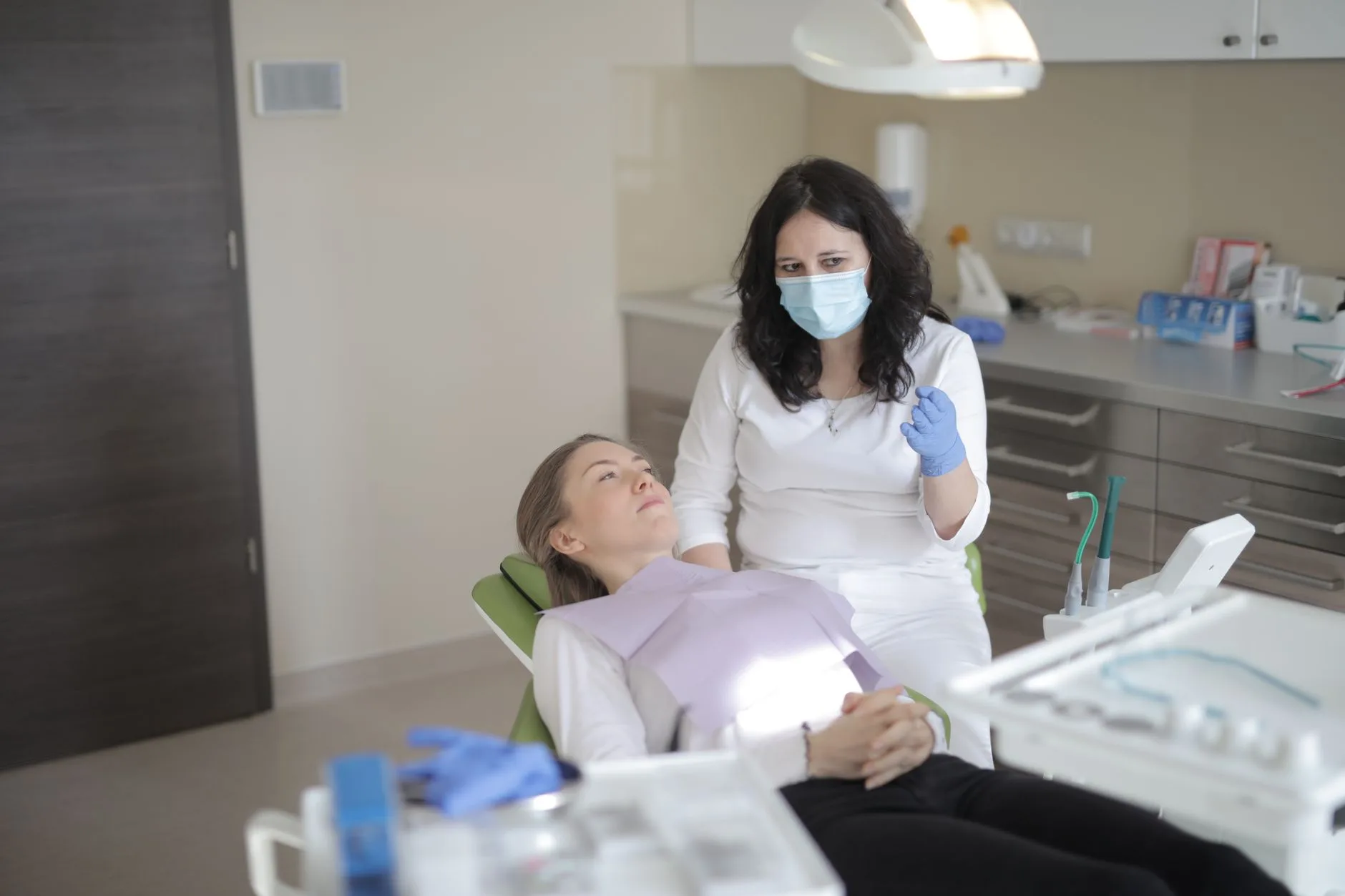 A dentist checks on a patient seated in a modern treatment room