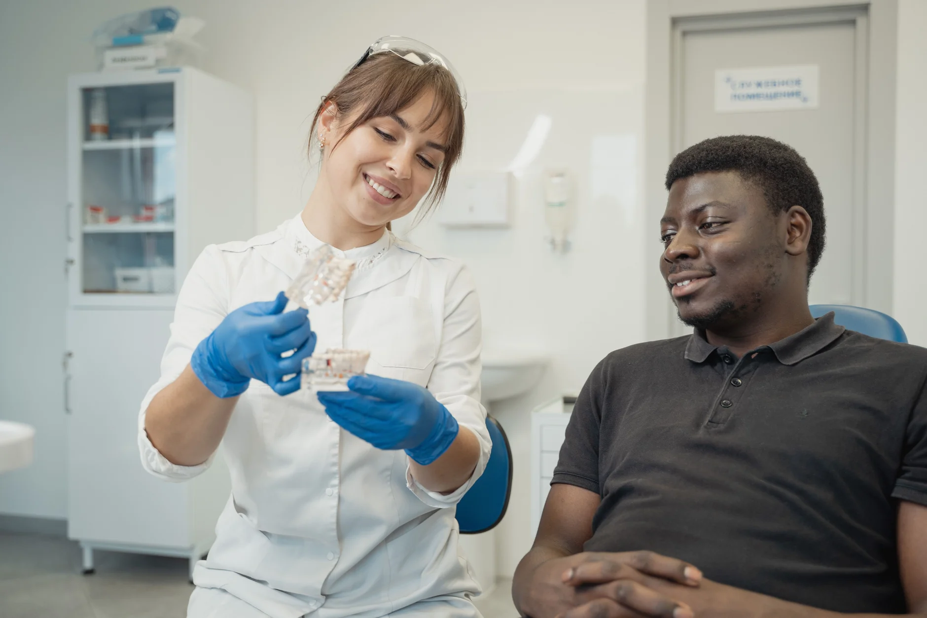 A dentist explains a dental model to a relaxed patient.